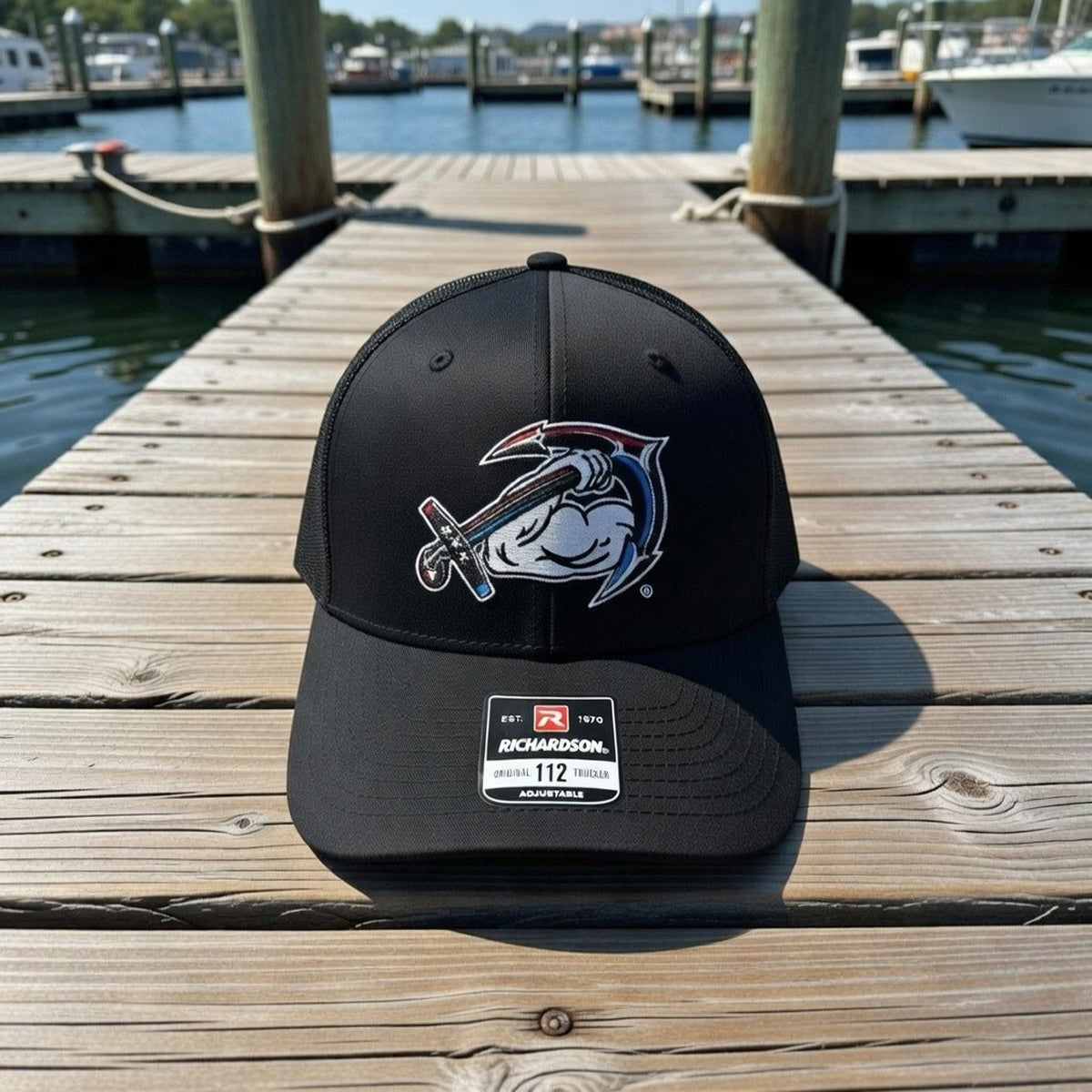 Black AMD cap with a logo on a wooden dock by the water
