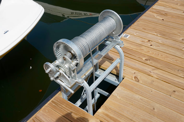 Boat lift mechanism on a wooden dock with boats in the background built by American Muscle Docks