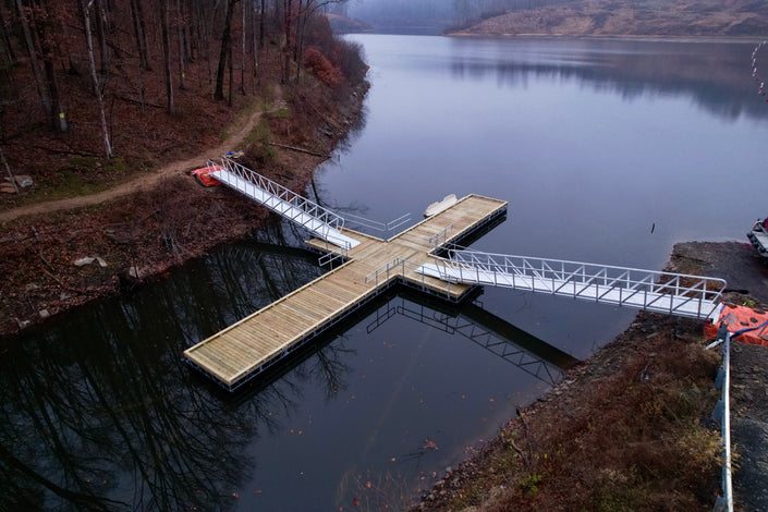Wooden dock extending into a lake with two gangways attached to hiking trail