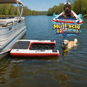 A dog swims toward a floating red and white Mutt-scle XL Floating Dog Ramp by American Muscle Docks & Fabrication, attached to a pontoon boat on a lake.