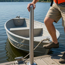 Person boarding a small boat on a dock using the Helping Hand with a calm lake and trees in the background