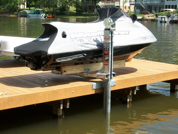 A covered jet ski is parked on a wooden dock above the water, supported by a metal boat lift system.