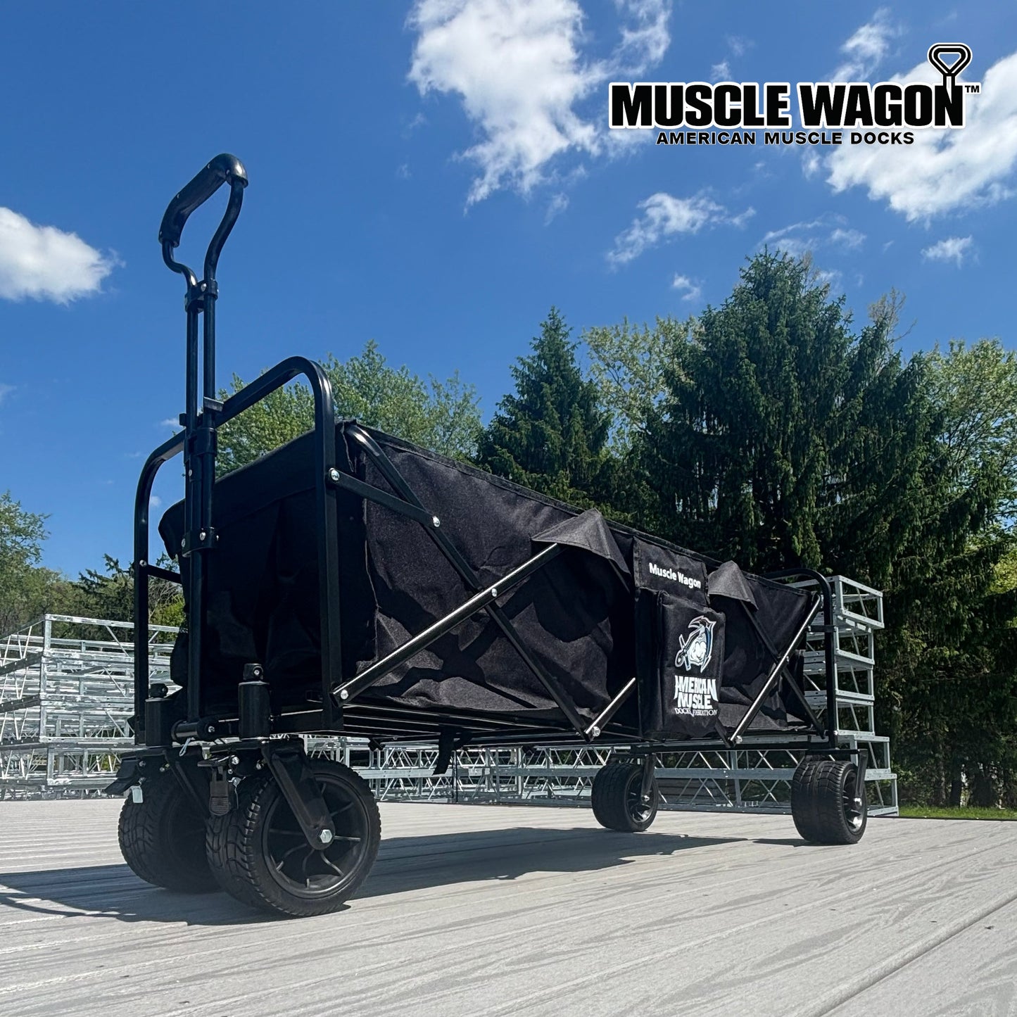A Collapsible Pull Wagon by American Muscle Docks with large wheels is shown outdoors on a deck, featuring the brand’s name on the side and in the top right corner.