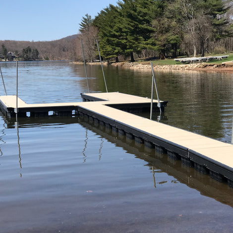 Steel channel dock extending into a calm lake with trees and mountains in the background.