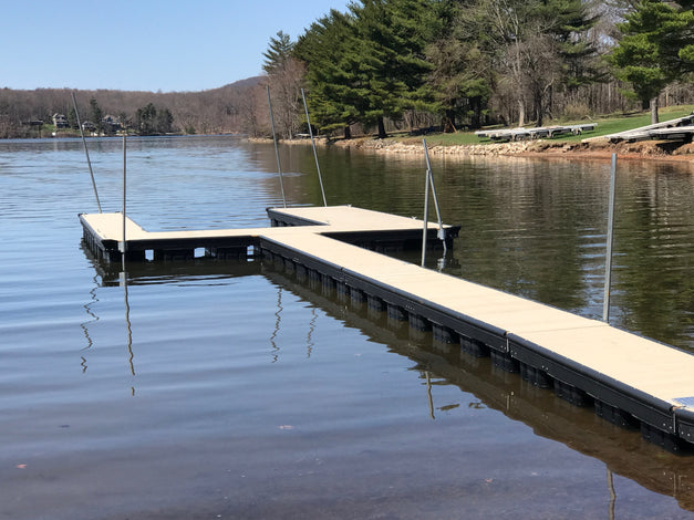 Steel channel dock extending into a calm lake with trees and mountains in the background.